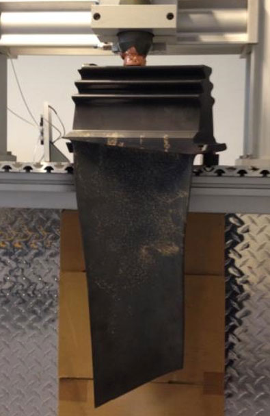 Large turbine blade with ultrasonic horn in test fixture.